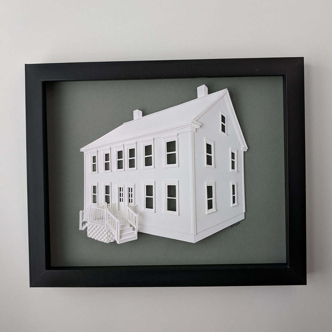a paper model of a house in a black frame