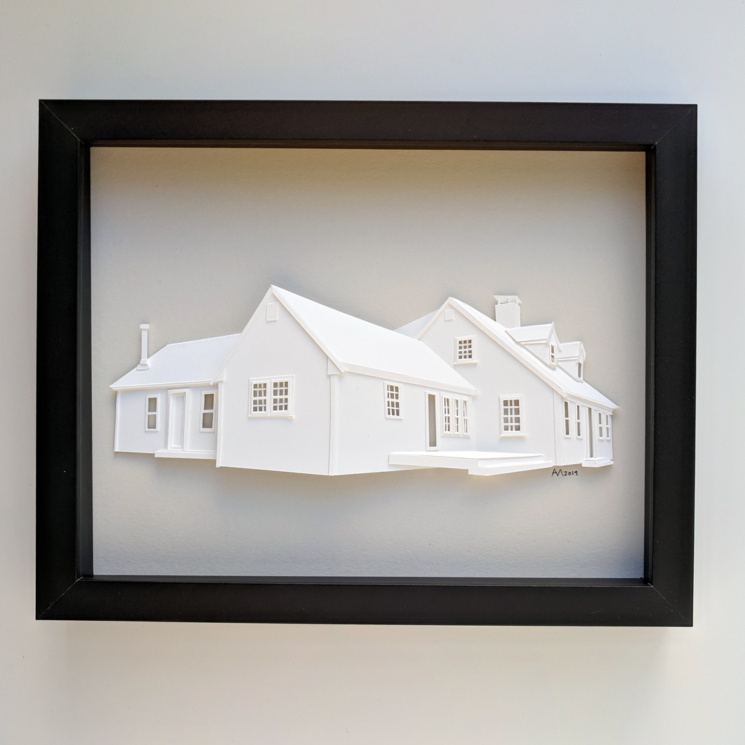 a paper cut of a house in a black frame