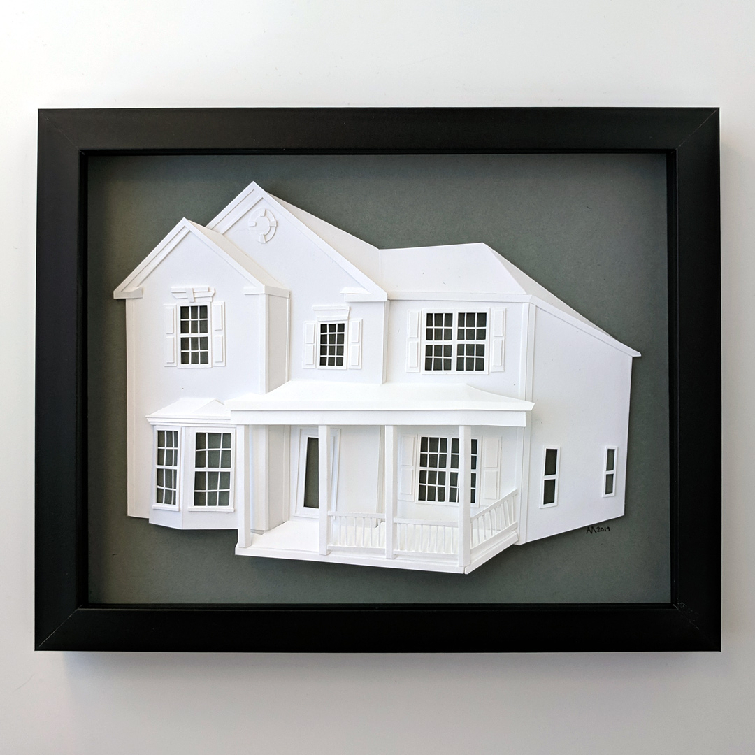 a paper model of a house in a black frame