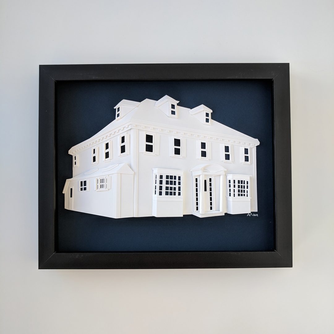 a paper model of a white house in a black frame