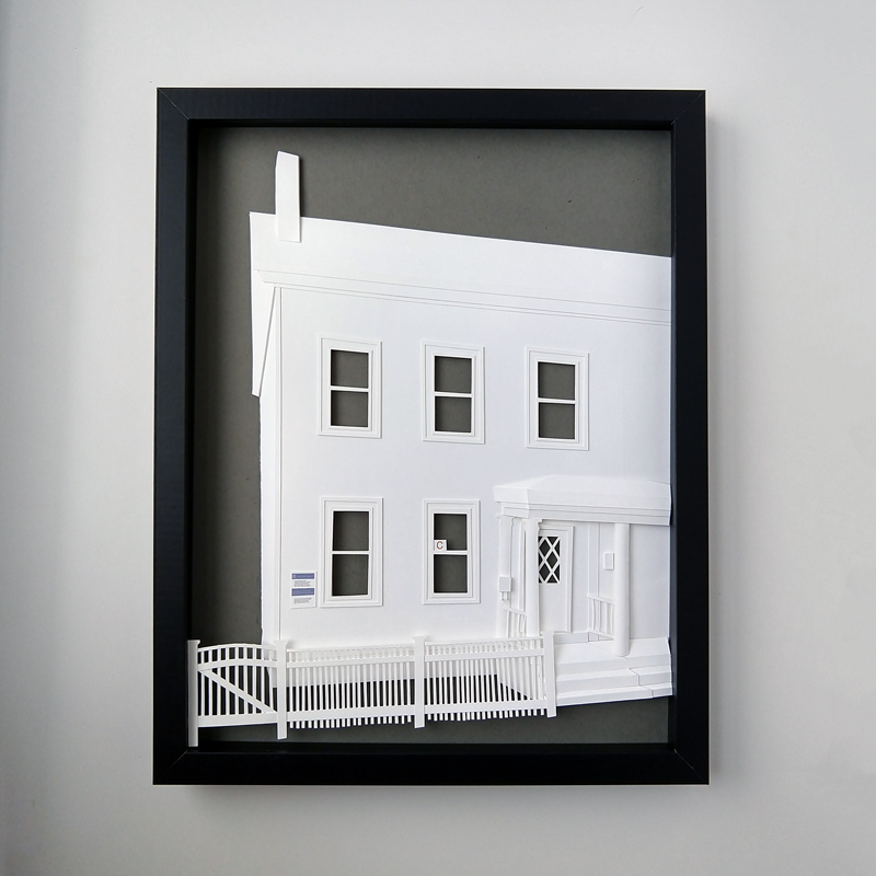 a paper cut out of a house in a black frame