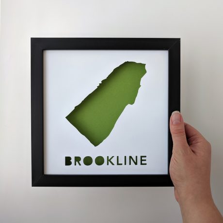 a person holding up a framed poster with the shape of a state