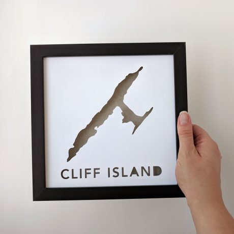 a person holding up a framed poster with the word cliff island
