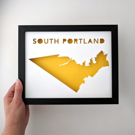 South Portland map with yellow background in black frame held in hand