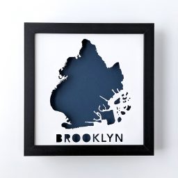 Framed map of Brooklyn, NYC cut out of white paper revealing a dark blue background