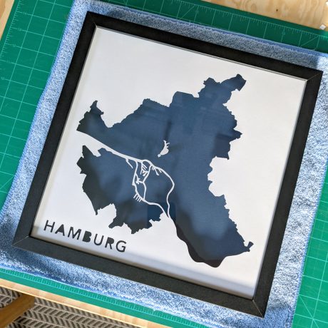 a framed map of hamburg on a green cutting mat