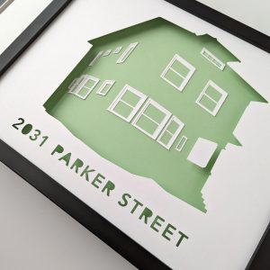 An angled view of a house portrait silhouette of a two story house with a mint green background in a black frame