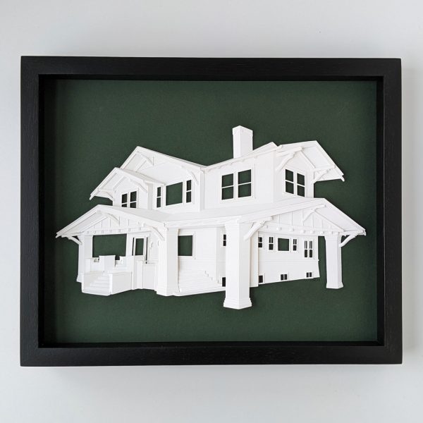 A portrait of a craftsman style home with a big carport on a dark forest green background in a black frame