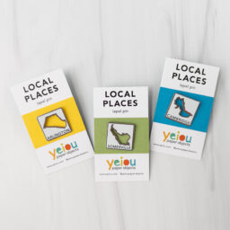 three small lapel pins mounted on cards with the words local places on them