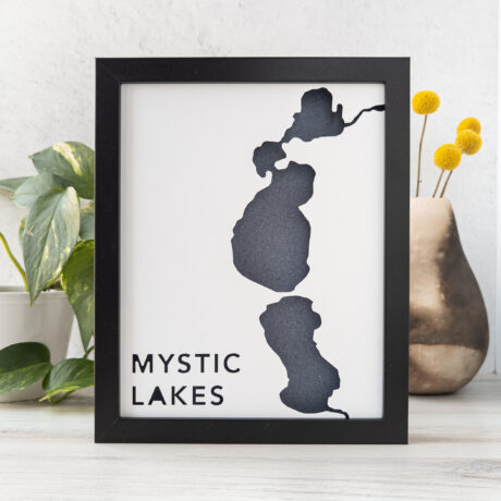 A framed map of the shoreline of the Mystic Lakes cut from white paper