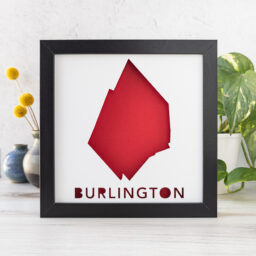 a picture frame with the shape of Burlington, MA cut out of white paper to reveal a red background