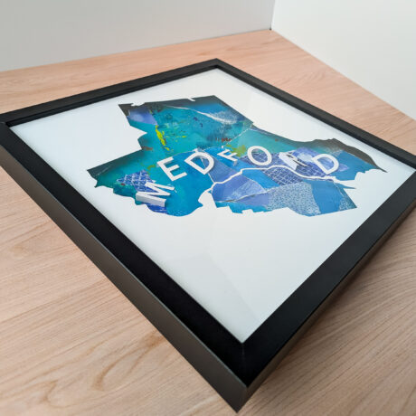 A photo of a blue collaged map of Medford, MA from an angle to the side so that the 3D letters can be seen clearly.