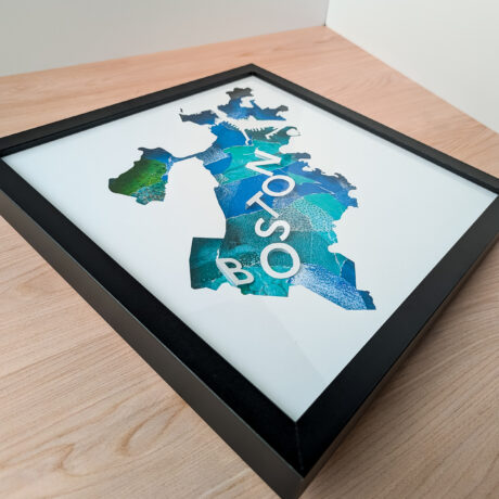 A photo of a blue collaged map of Boston, MA from an angle to the side so that the 3D letters can be seen clearly.